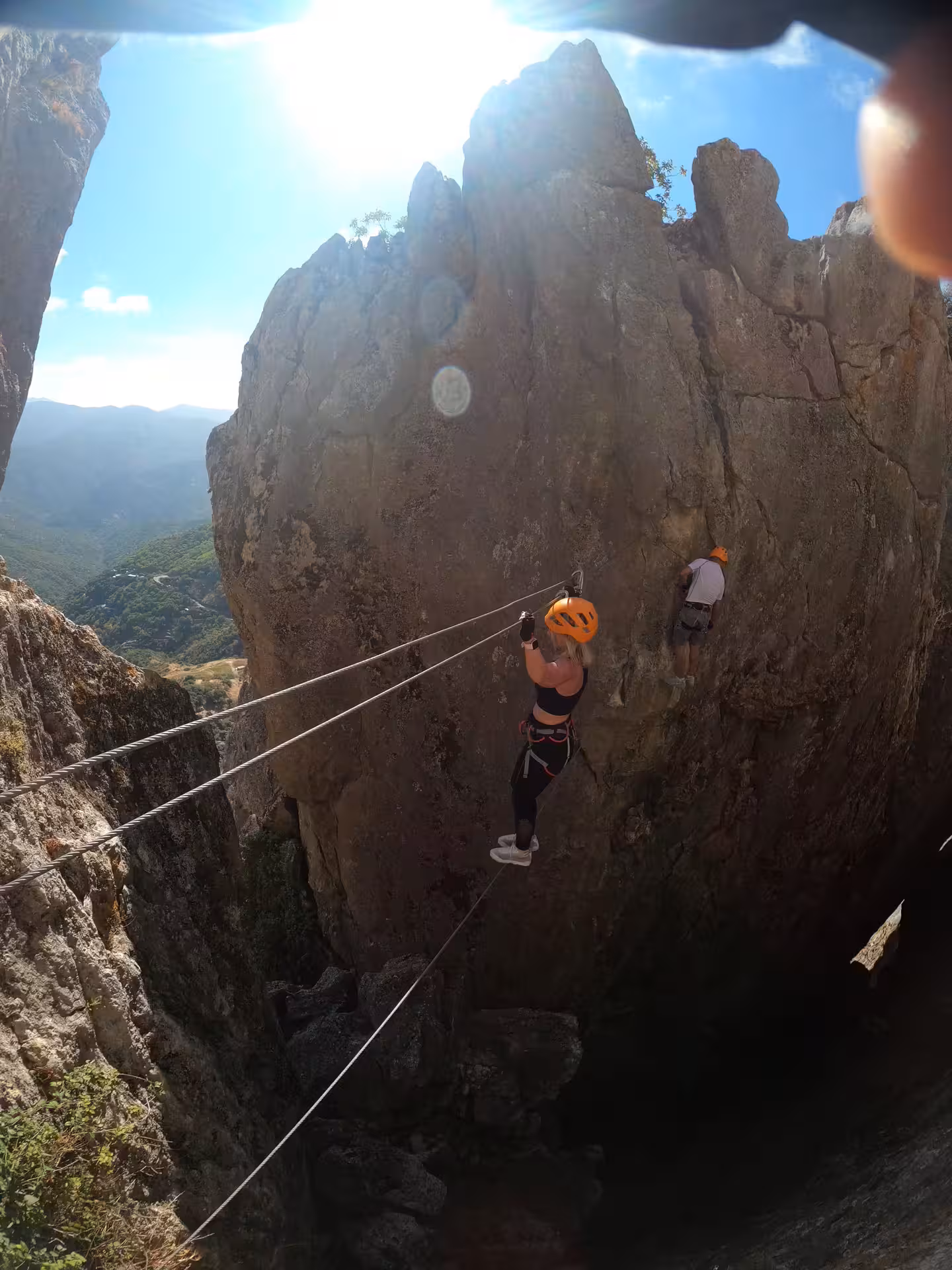 Adventurer crossing a high wire on the Via Ferrata in Benalauría with stunning views of Costa del Sol.