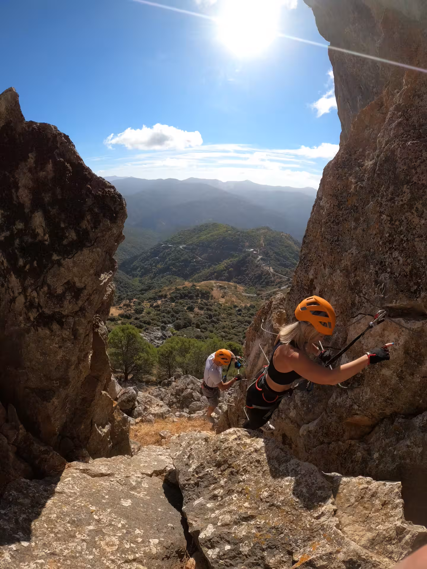 Climbers tackling a sunlit Via Ferrata route with panoramic views of Benalauría, Costa del Sol in the background.