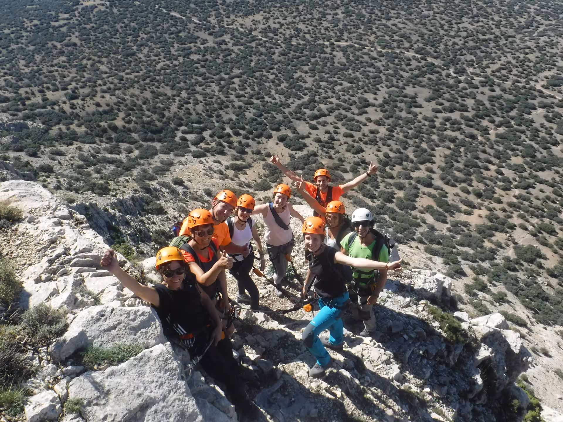 Grupo con cascos celebra en la cima tras vía ferrata en Montalbán, Teruel, experiencia nivel iniciación