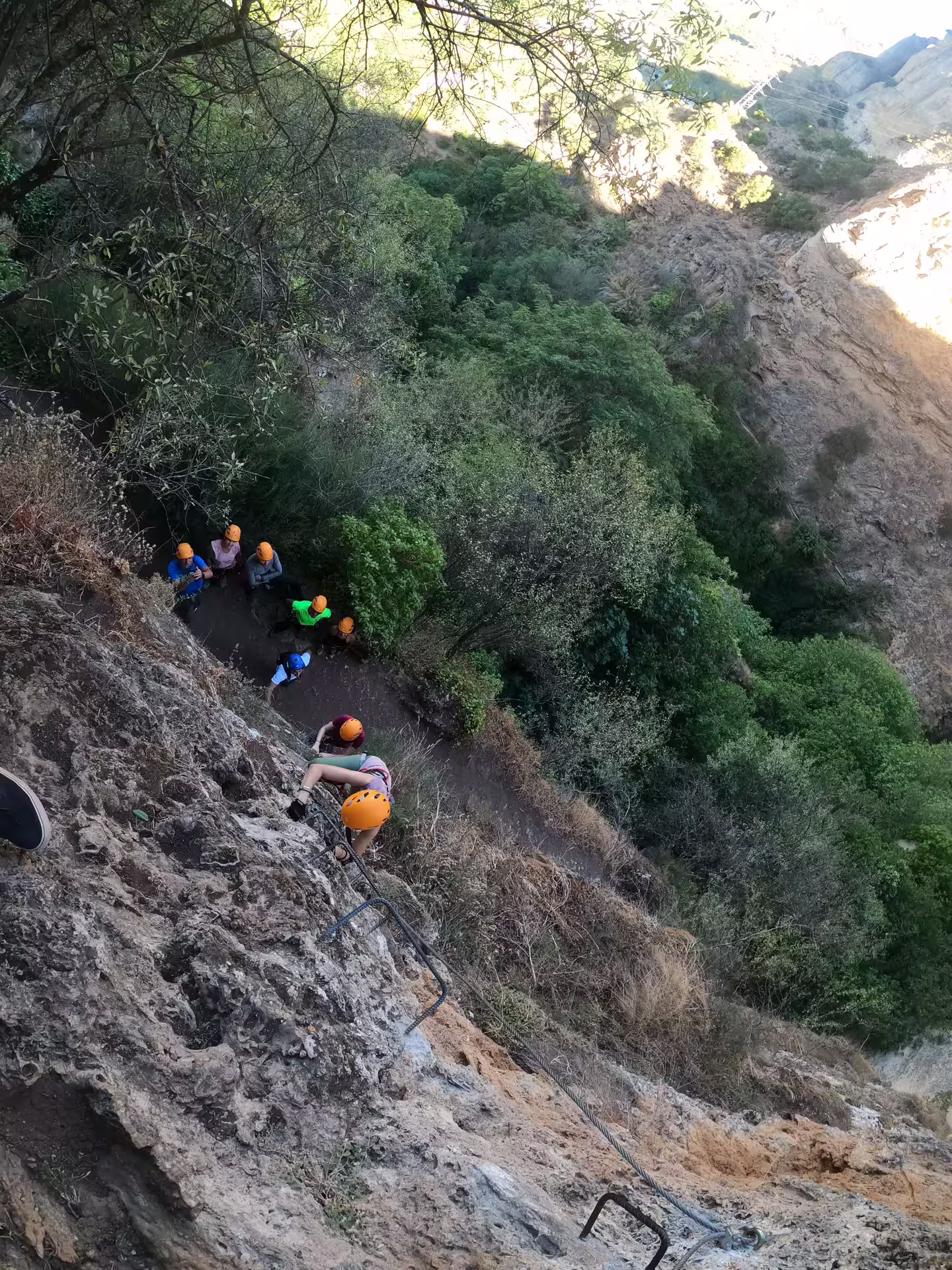 Adventurers climb the rugged Via Ferrata Tajo de Ronda, surrounded by breathtaking cliffs and lush greenery in Ronda, Spain.