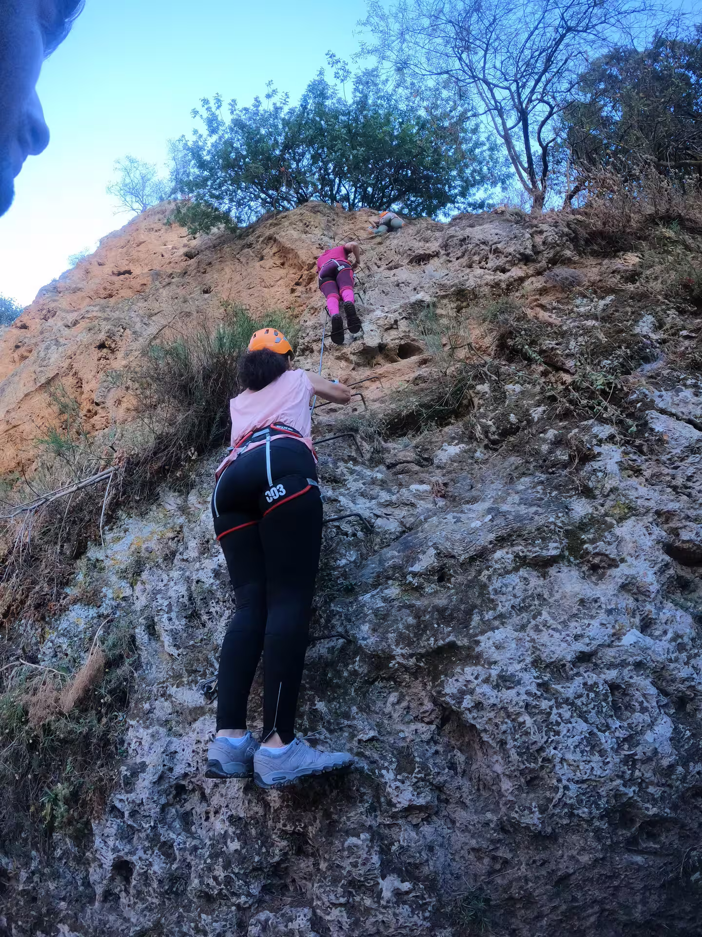 Two climbers with helmets and harnesses ascending rocky via ferrata route on guided Tajo de Ronda tour