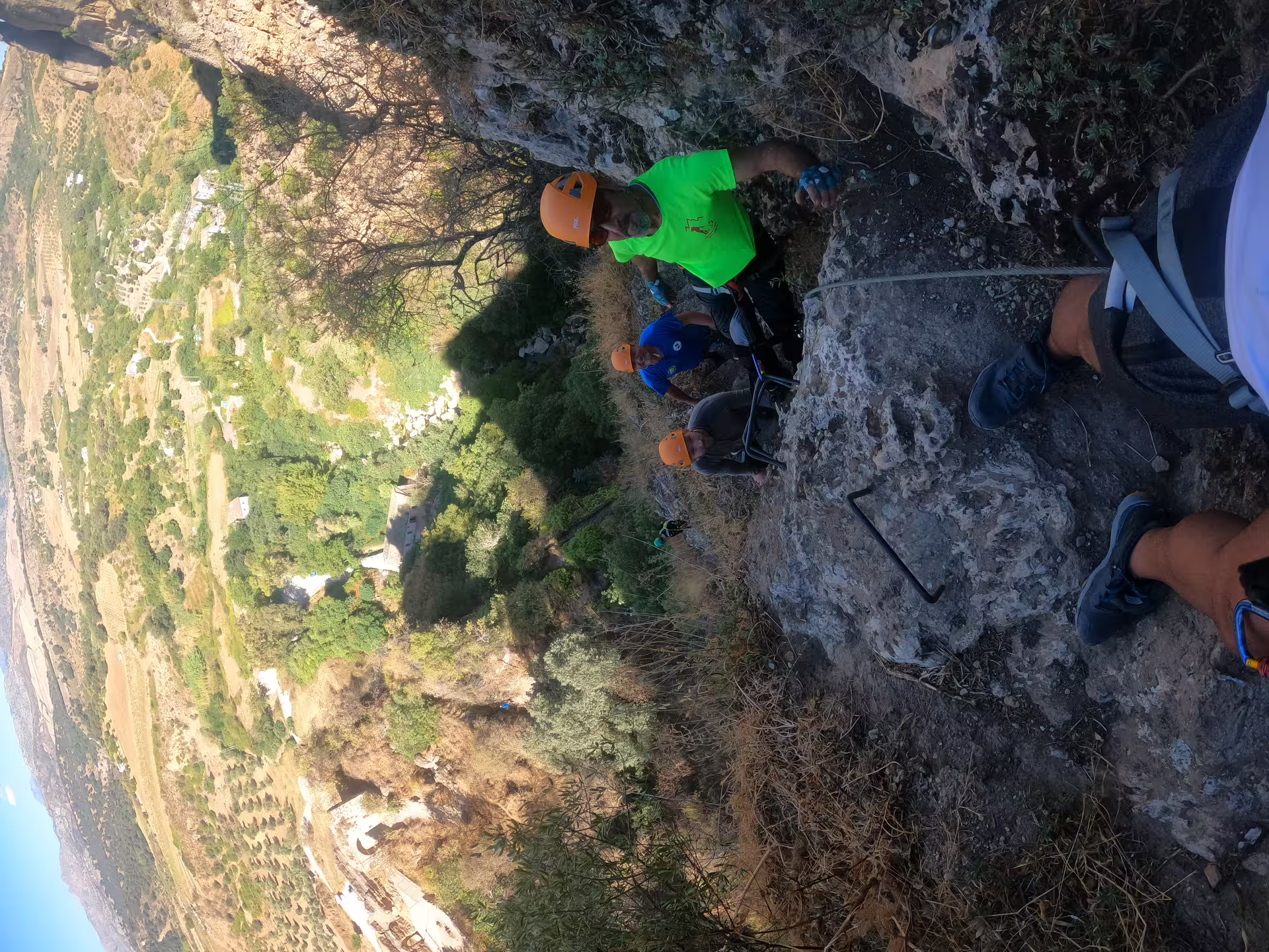 Guided via ferrata group climbing Tajo de Ronda cliff face with harnesses and helmets above scenic gorge