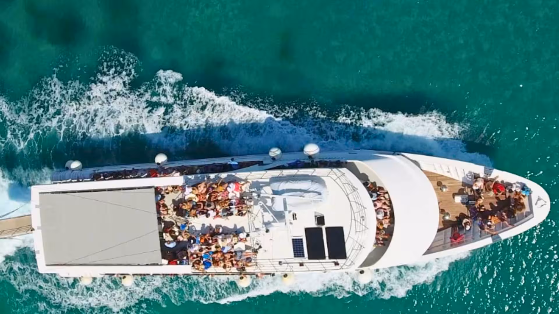 Aerial view of a cruise ship sailing the turquoise waters between the Aeolian Islands.