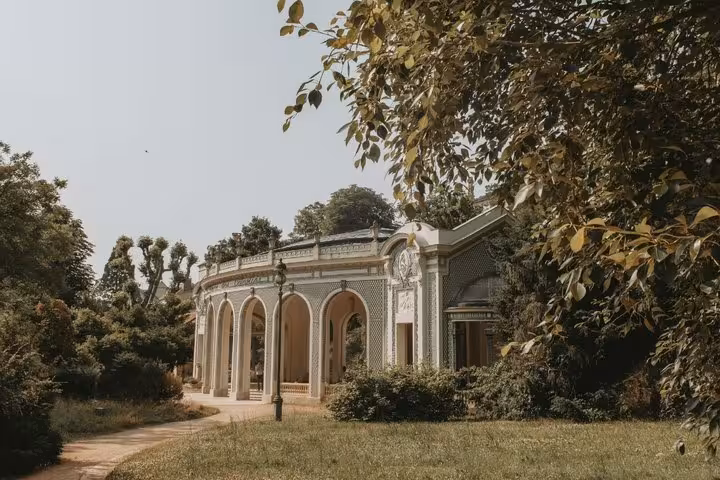 Elegant neoclassical pavilion with arched colonnades surrounded by lush greenery in Vichy, France
