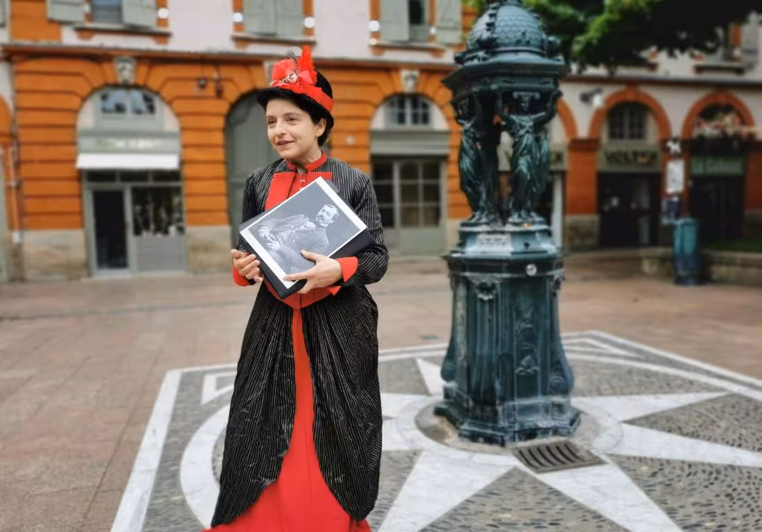 Costumed guide in Victorian dress holding historical photo during 19th-century Toulouse Saint-Georges district tour