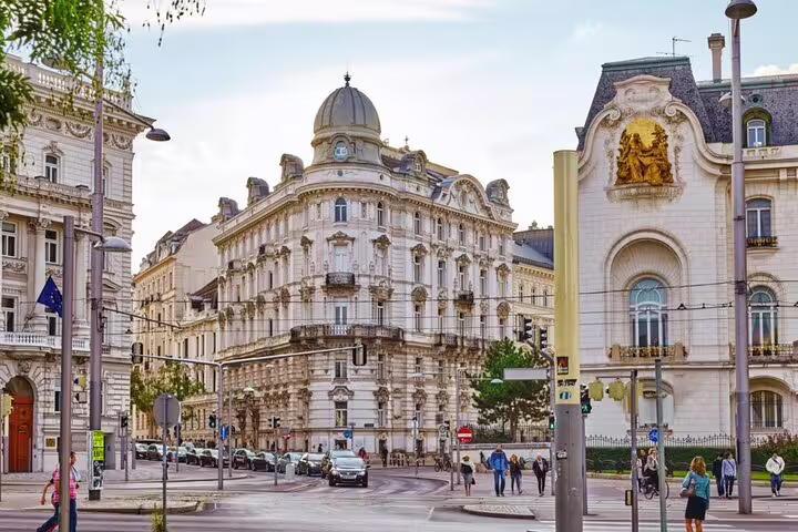 Ornate Viennese baroque buildings at a city intersection with pedestrians and European Union flag