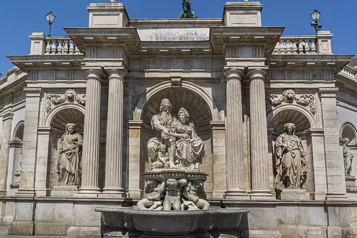 Ornate Baroque fountain and classical statues at a grand Vienna monument facade