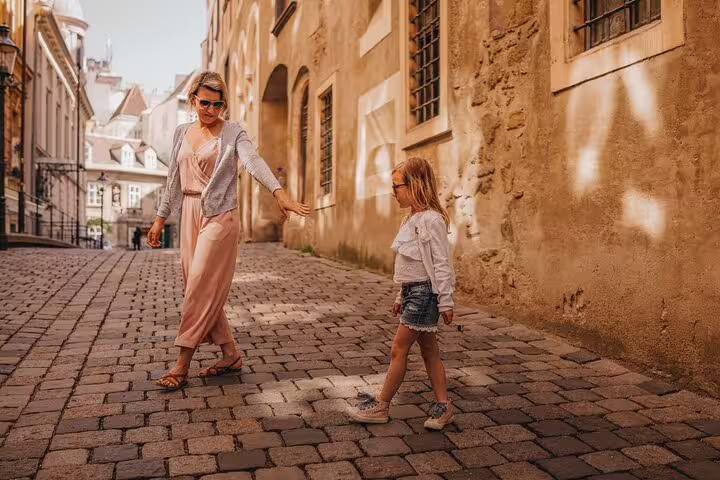 Family exploring charming cobblestone streets in Vienna on a private tour, capturing city highlights and cultural experiences.