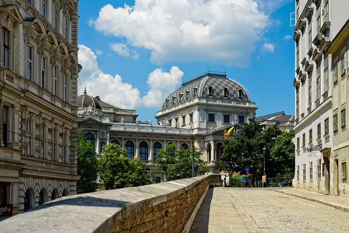 Historic Viennese baroque buildings and cobblestone street under blue sky
