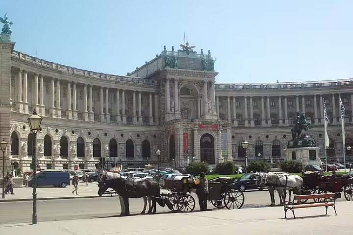 Horse-drawn carriages in front of the grand Hofburg Palace facade in Vienna, Austria