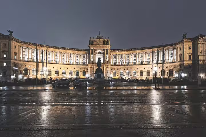 Hofburg Palace illuminated at night with wet cobblestone square in Vienna, Austria