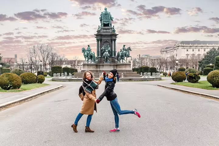 Two happy tourists pose in front of Vienna's Maria Theresa Monument, capturing the essence of a private tour of Vienna's hidden gems.