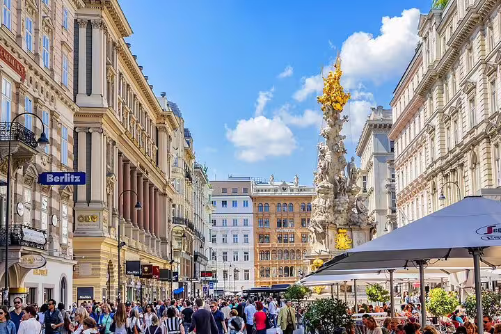 Crowded Graben pedestrian street in Vienna with Plague Column and historic baroque buildings on sunny day