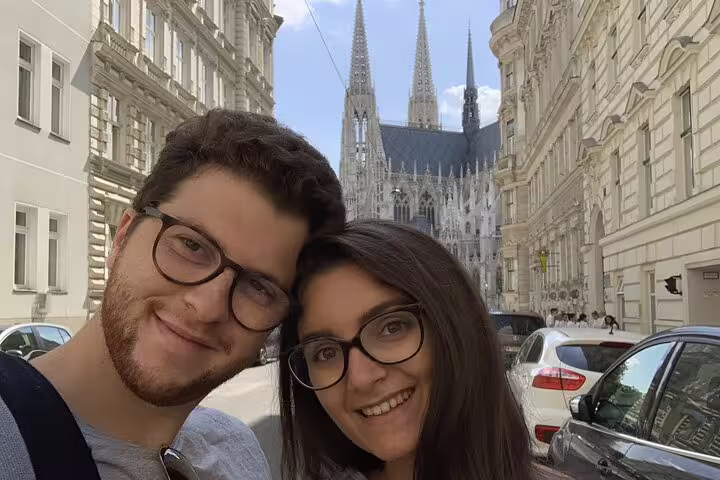 Couple taking selfie in Vienna street with Votivkirche Gothic cathedral spires in background