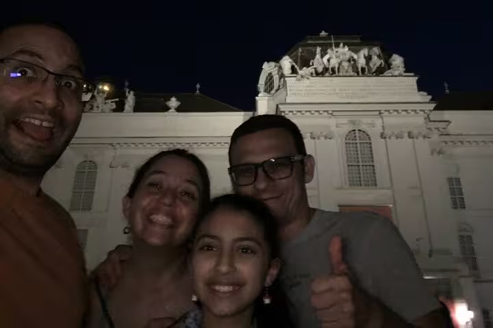 Family of four smiling at night in front of illuminated Belvedere Palace in Vienna