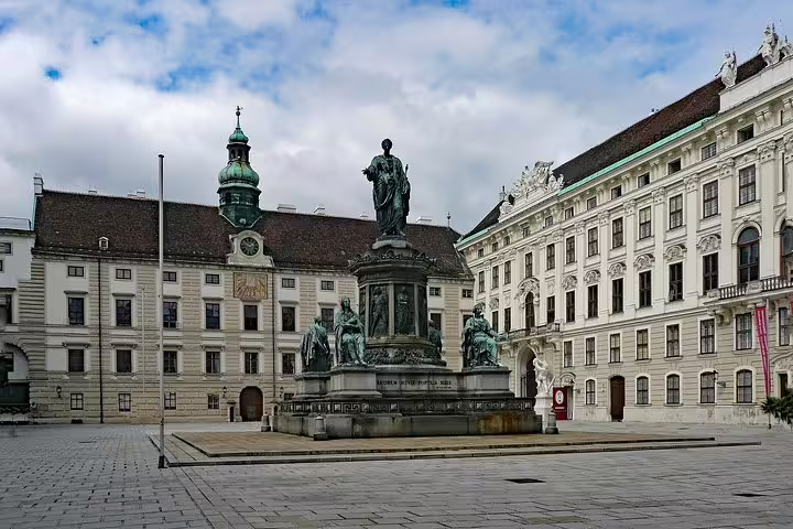 Bronze monument in Vienna's Hofburg Palace courtyard surrounded by ornate Baroque architecture