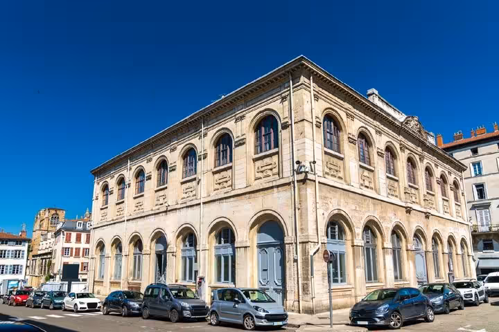 Historic neoclassical stone building with arched windows in Vienne, France on a sunny day