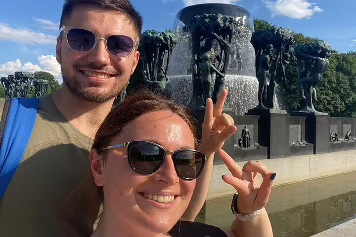 Couple taking selfie at Vigeland Park fountain with bronze sculptures in Oslo