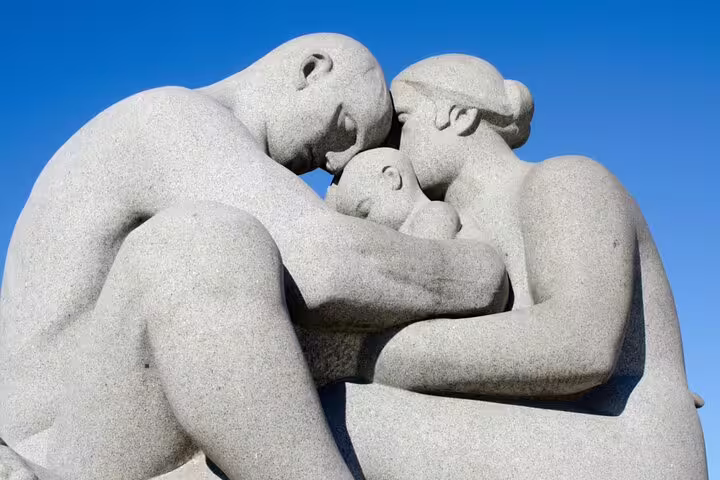 Granite sculpture of two adults embracing a child at Vigeland Park Oslo