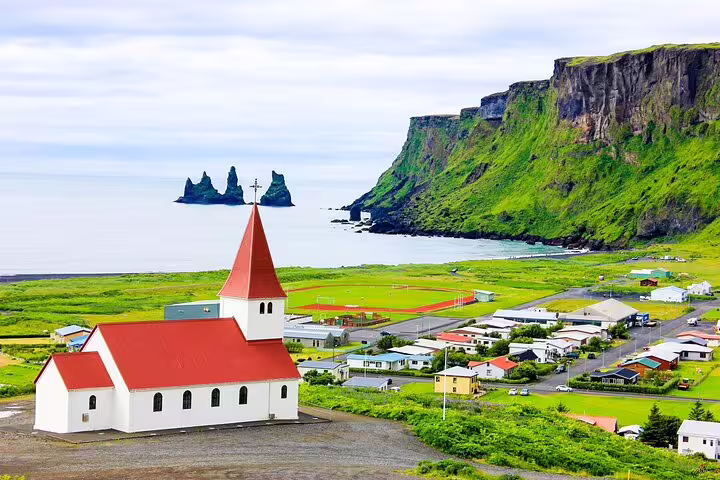 Scenic Vik village with red-roofed church and Reynisdrangar sea stacks on Iceland South Coast tour