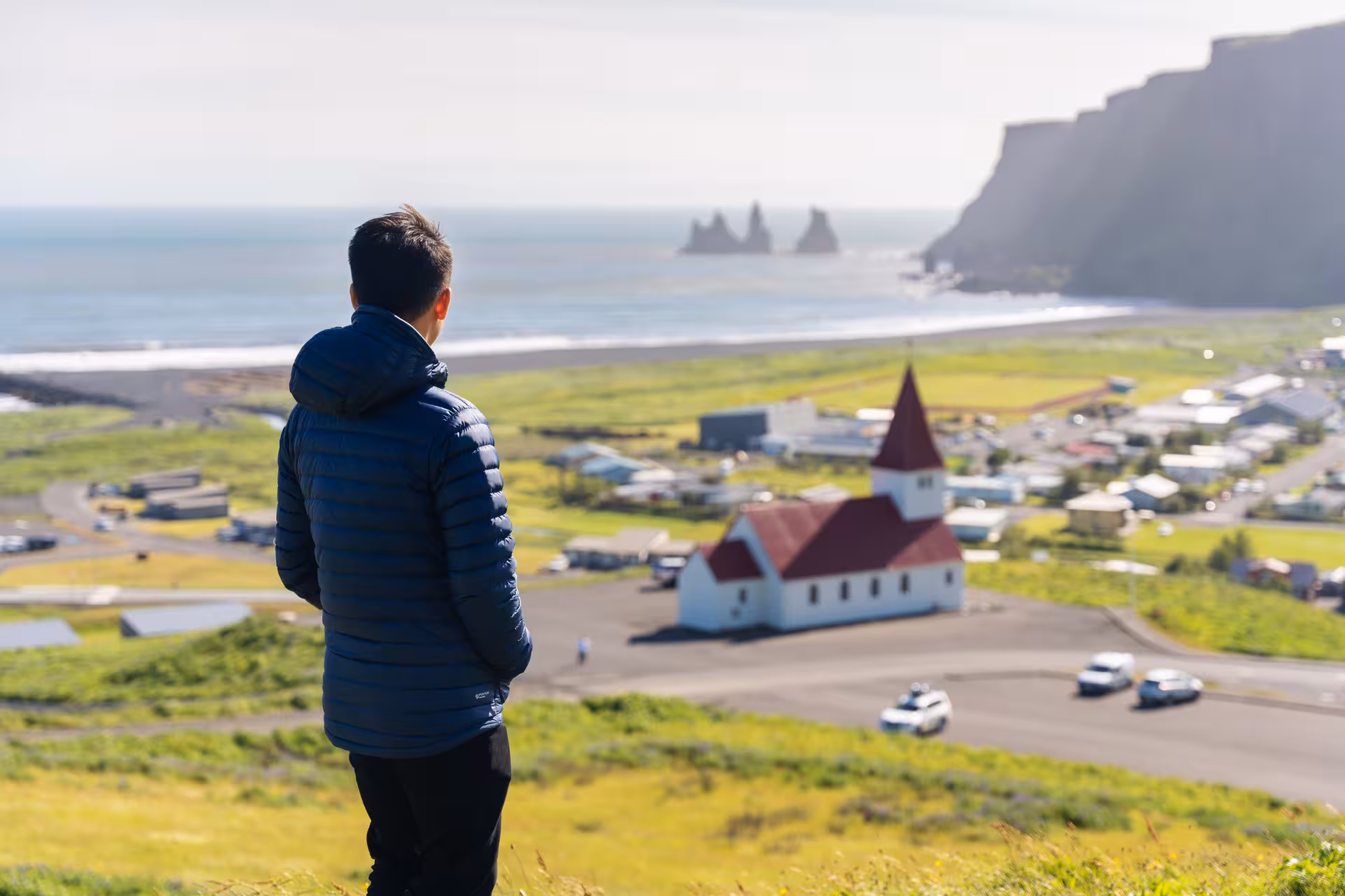 Traveler admires Vik's stunning coastline and iconic church on South Coast Private Tour, Iceland.