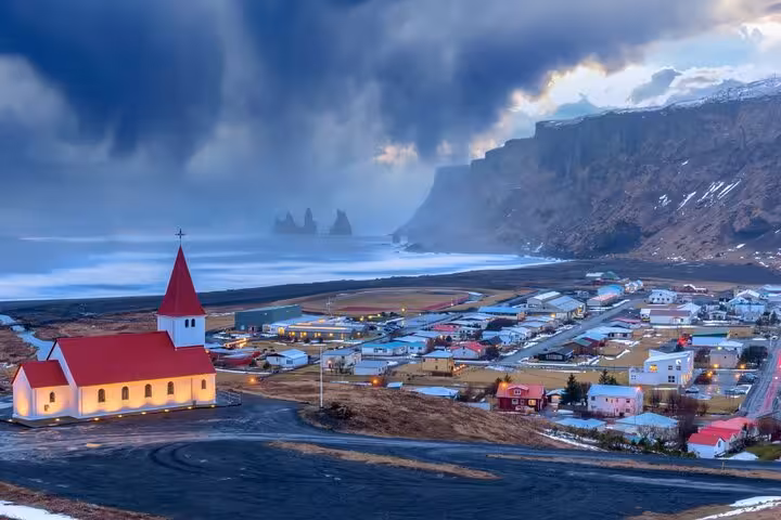 Aerial view of Vík village with red church, black sand beach, and dramatic cliffs on Iceland's South Coast