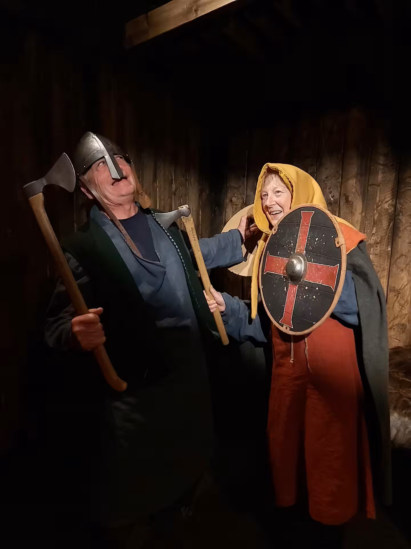 Two people in Viking costumes holding axes and shield with red cross at Skagafjordur farm