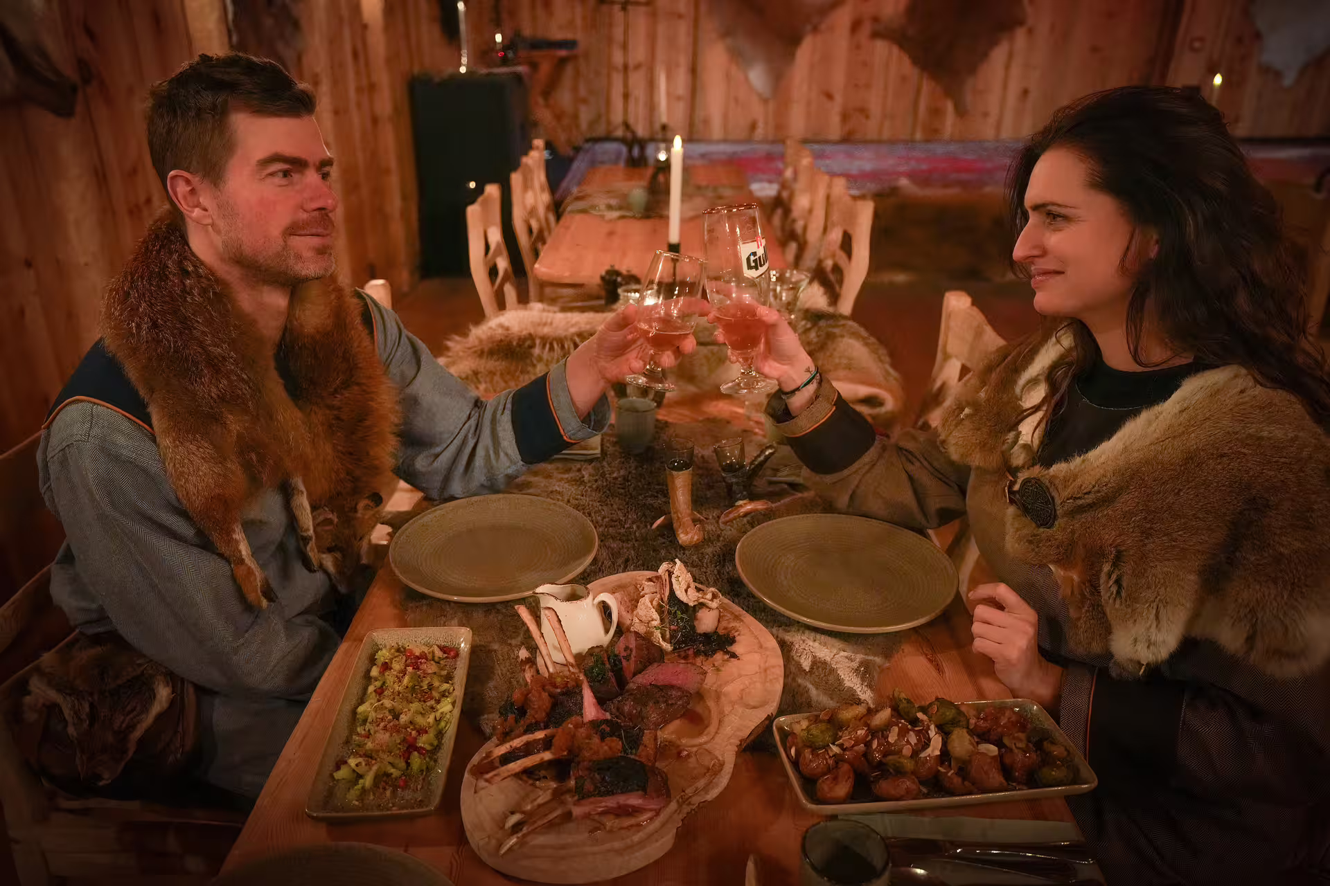Couple in Viking attire toasting over a traditional Icelandic feast by candlelight during a witchcraft and magic experience