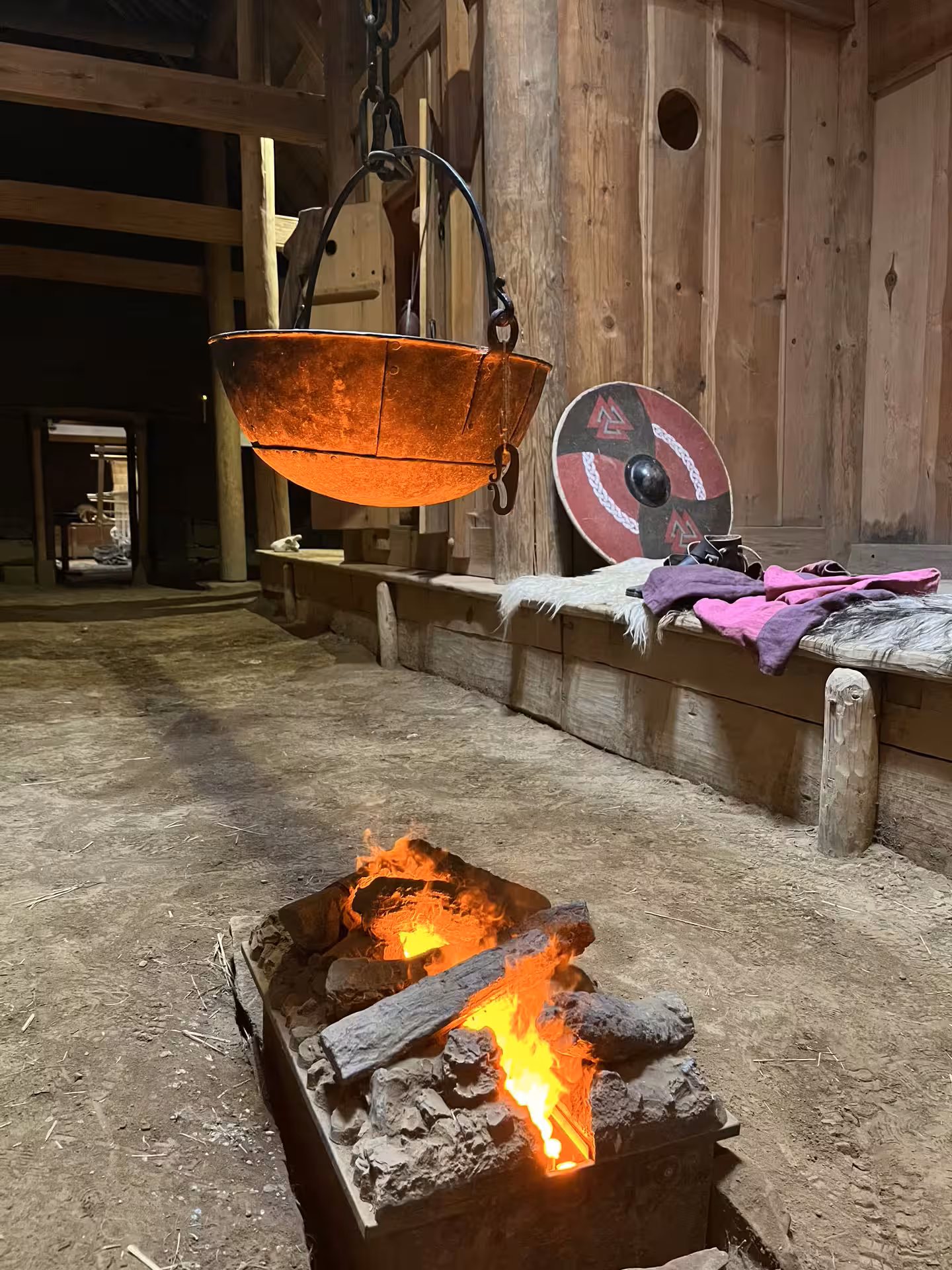 Authentic Viking longhouse interior with glowing open fire shield and iron cauldron on a Viking Valley Iceland cultural adventure