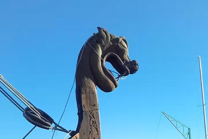 Viking longship dragon head prow wooden carving against blue sky in Normandy