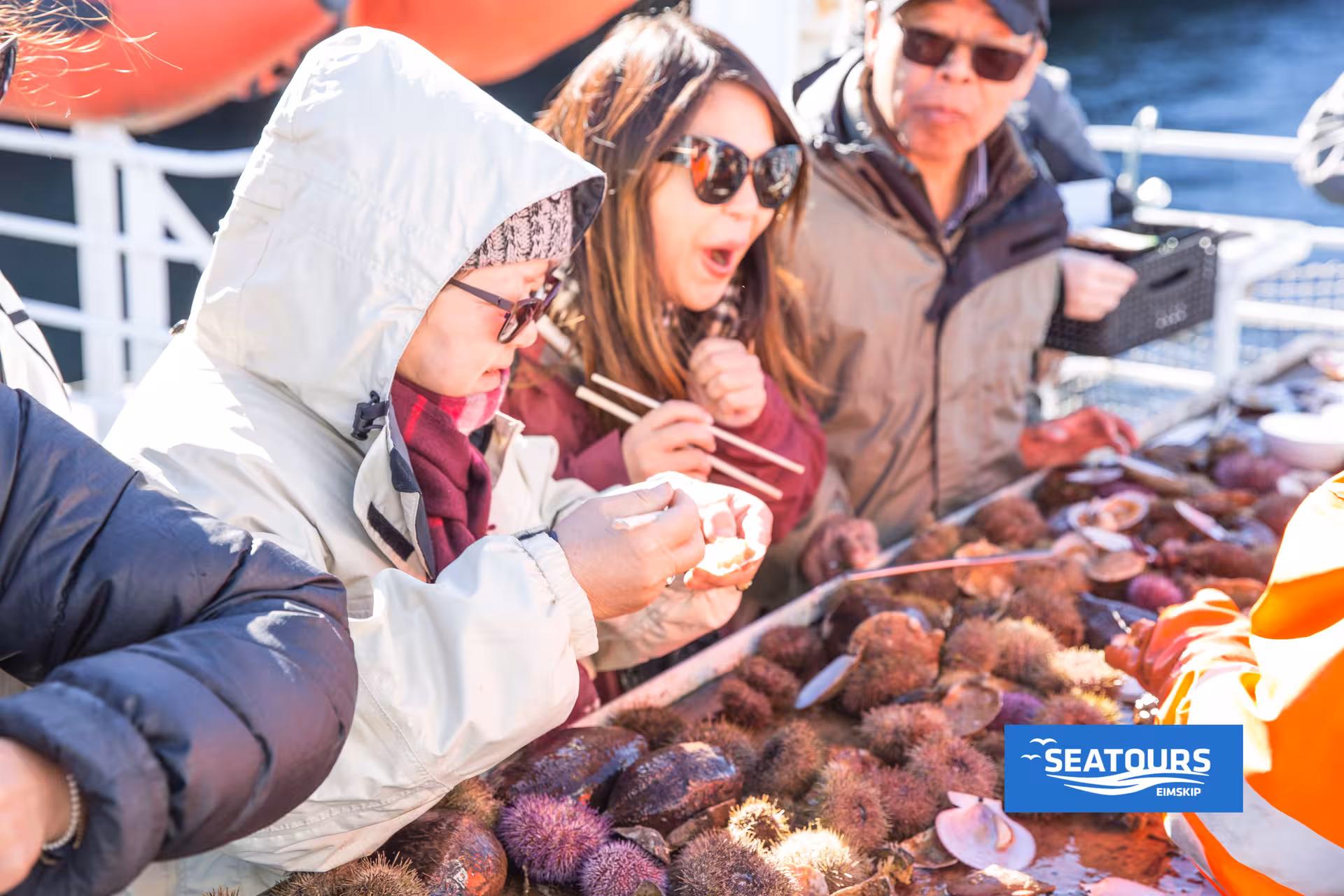 Guests sampling fresh sea urchin and shellfish on boat, Iceland Viking Sushi Tour seafood tasting
