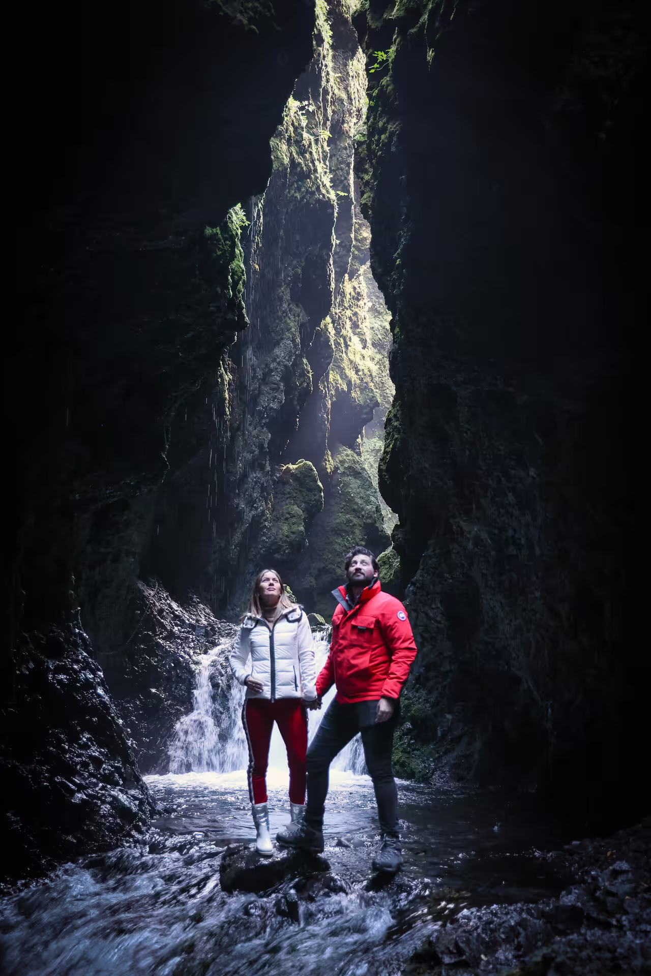 Two travelers explore a dramatic mossy Iceland canyon with a hidden waterfall on a Viking South Coast tour.