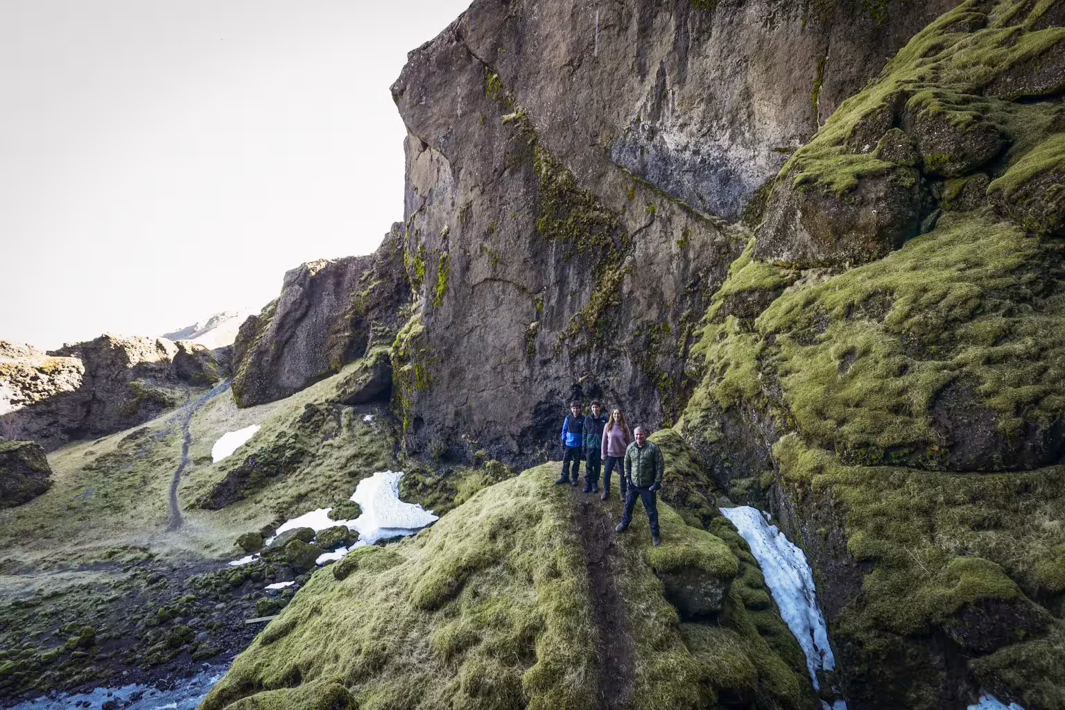 Hikers explore a mossy Viking Valley canyon with snow patches on Iceland's scenic South Coast summer adventure tour