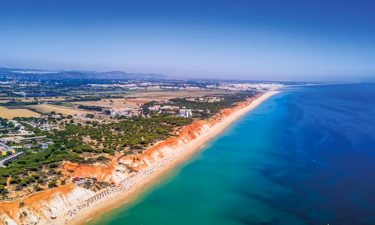 Aerial view of Vilamoura Algarve coastline with red cliffs turquoise sea perfect for sunset catamaran boat tour