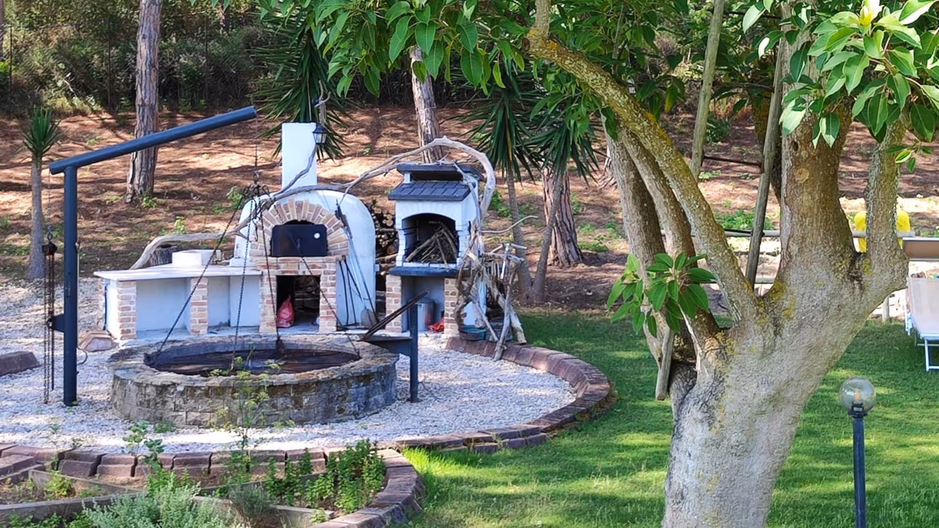 Charming villa garden with traditional brick pizza ovens set amidst lush greenery for an authentic cooking experience.