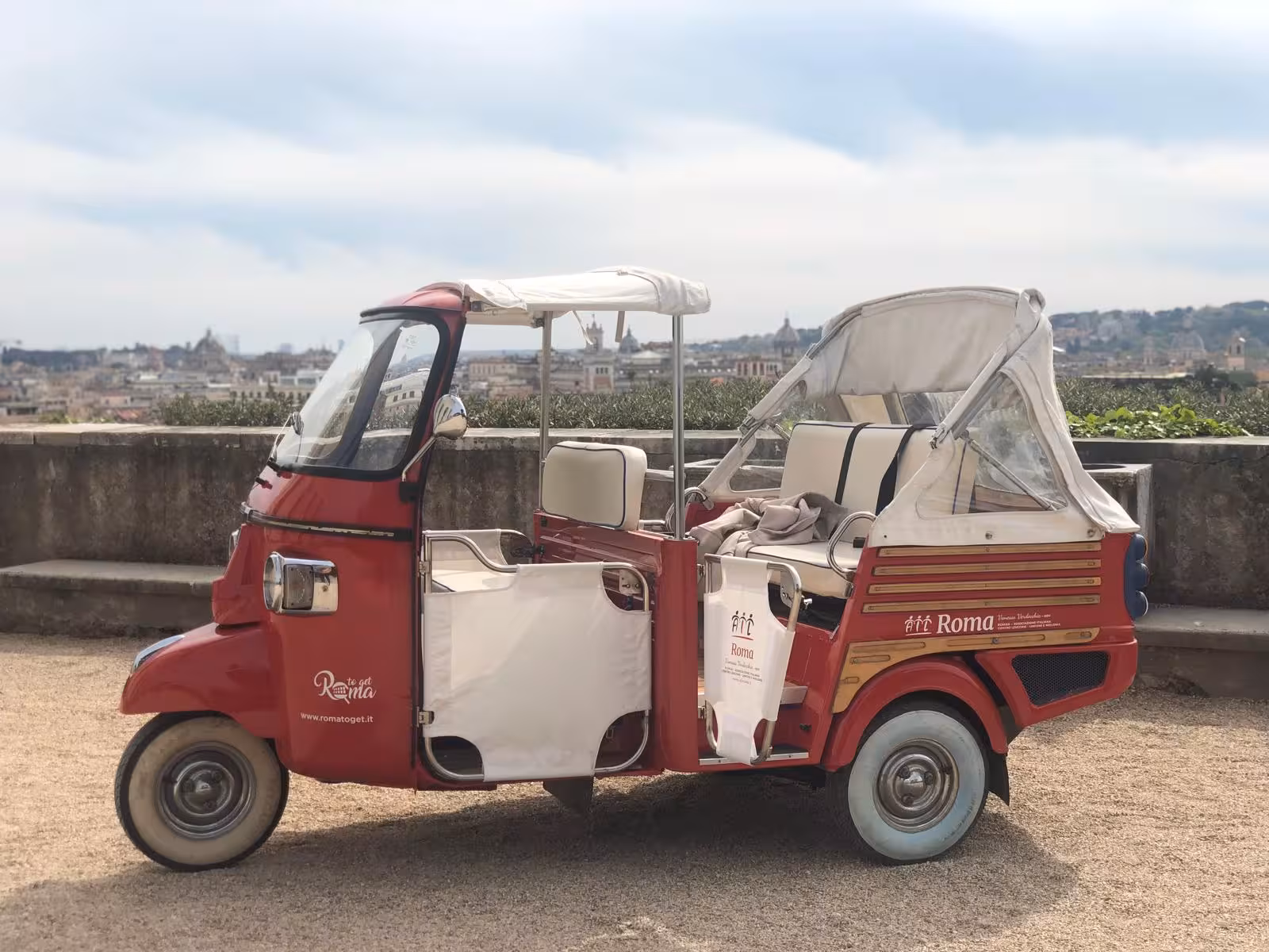 Red tuk-tuk on Villa Medici Combo Tour with panoramic views of Rome in the background.