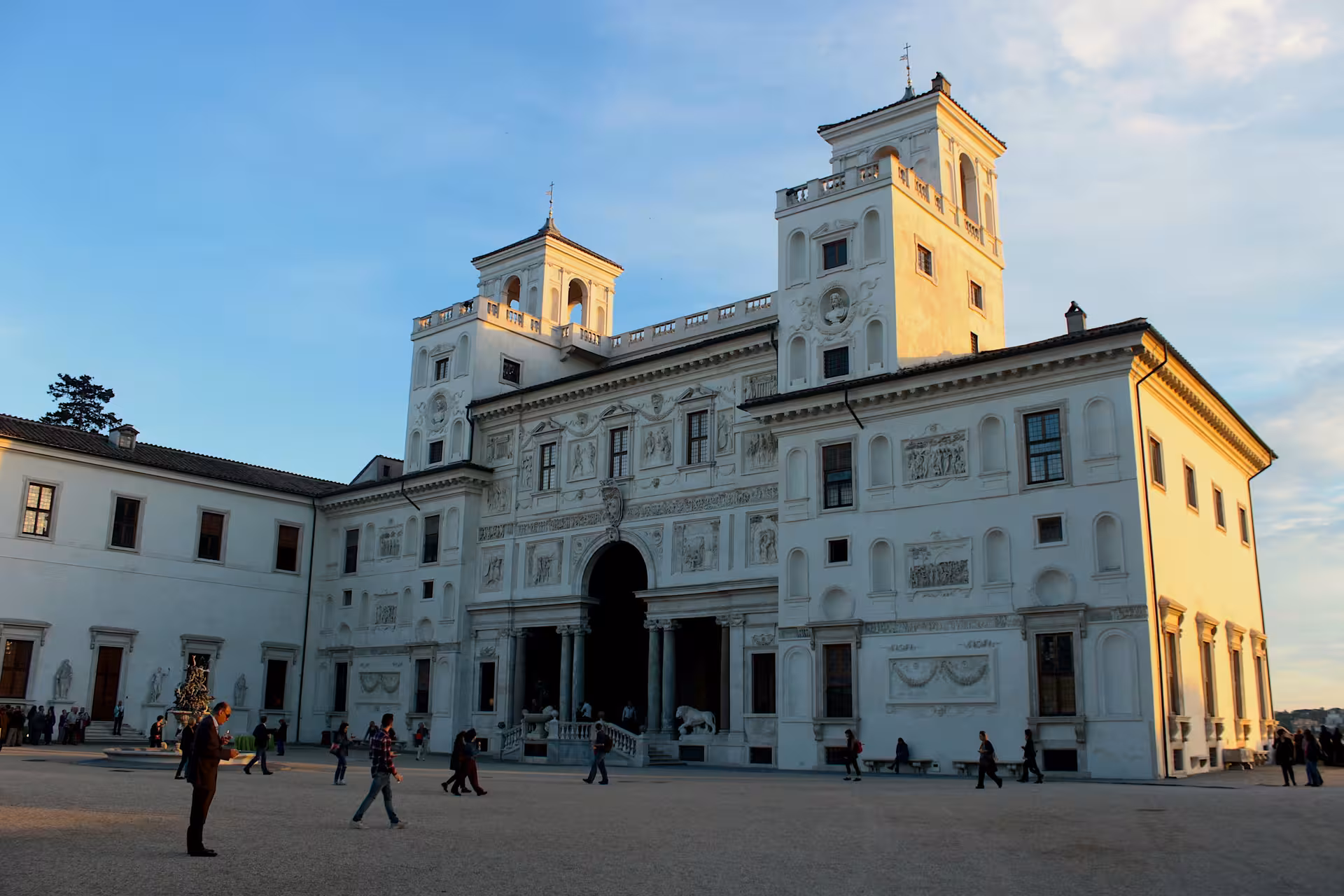 Tourists explore the historic Villa Medici in Rome at sunset, showcasing its stunning architecture and cultural heritage.