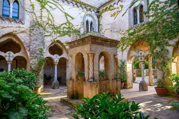 Explore the enchanting medieval courtyard of Villa Rufolo in Ravello, adorned with lush greenery and historic architecture.