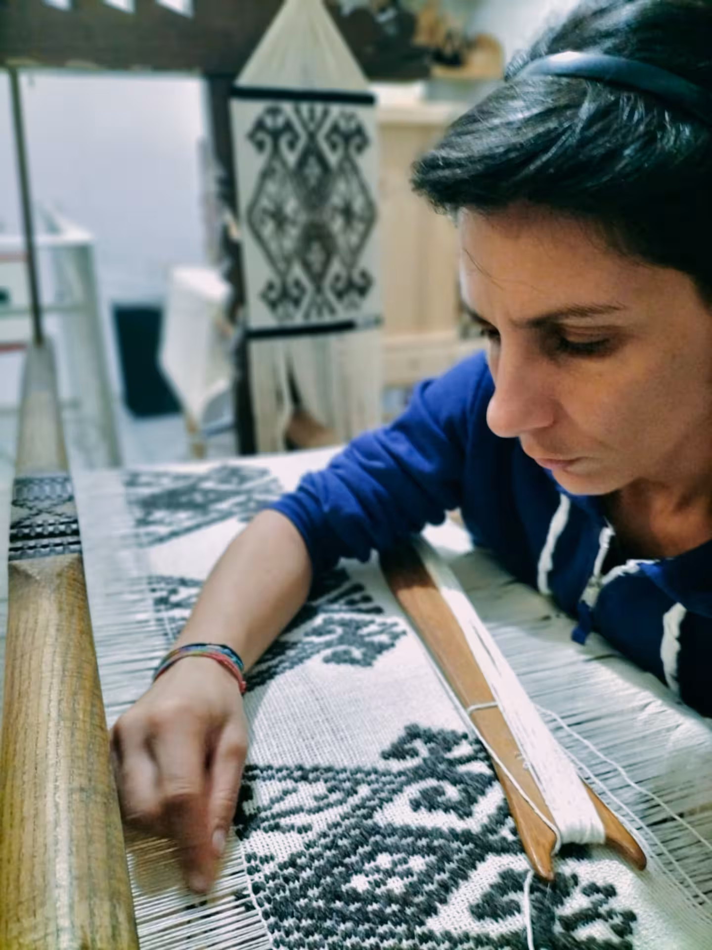 Artisan weaving intricate patterns on a loom at Villacidro Sardinian weaving workshop, highlighting traditional craftsmanship.