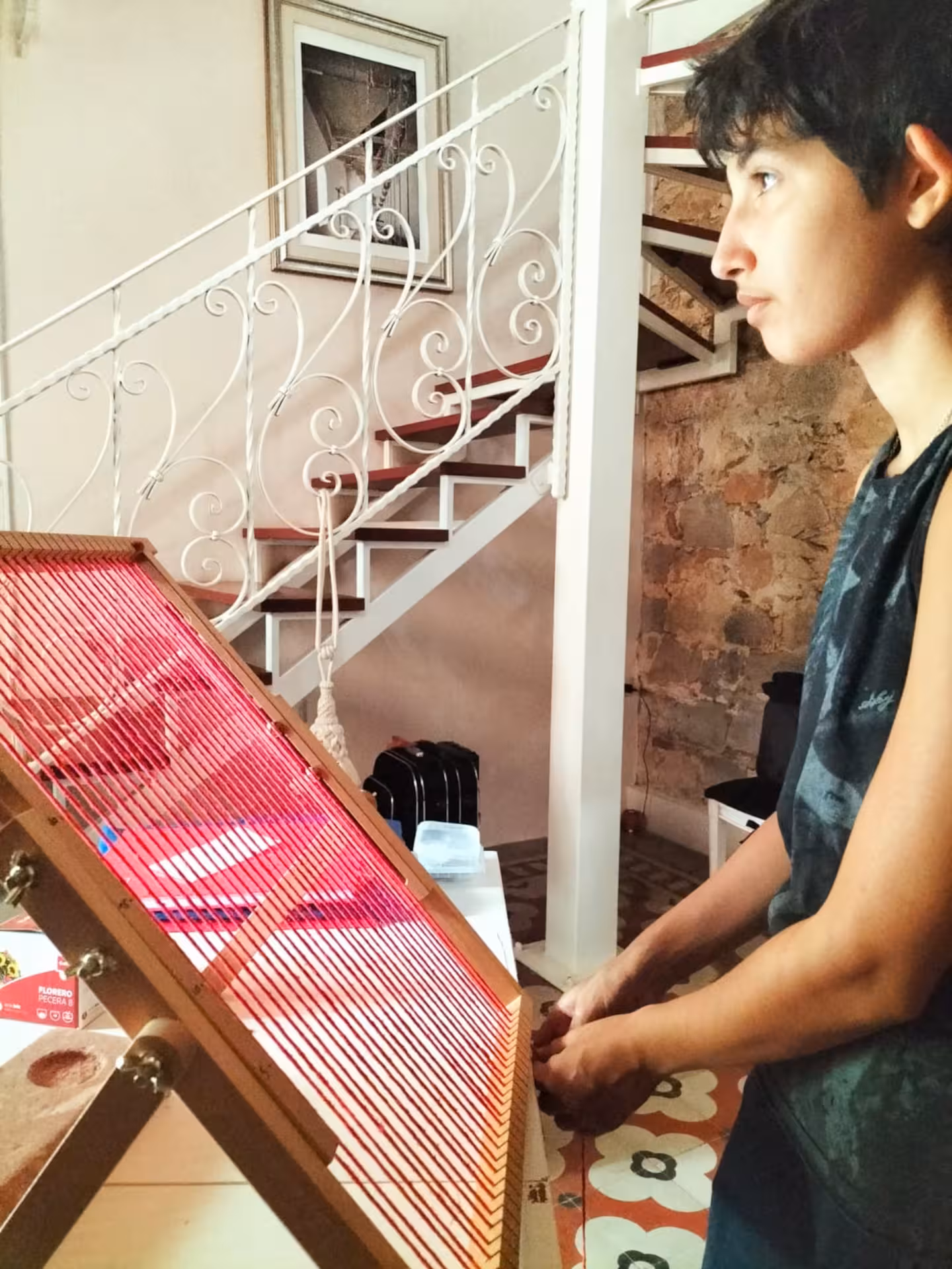 A focused individual working on a vibrant red loom in a traditional Villacidro weaving workshop.