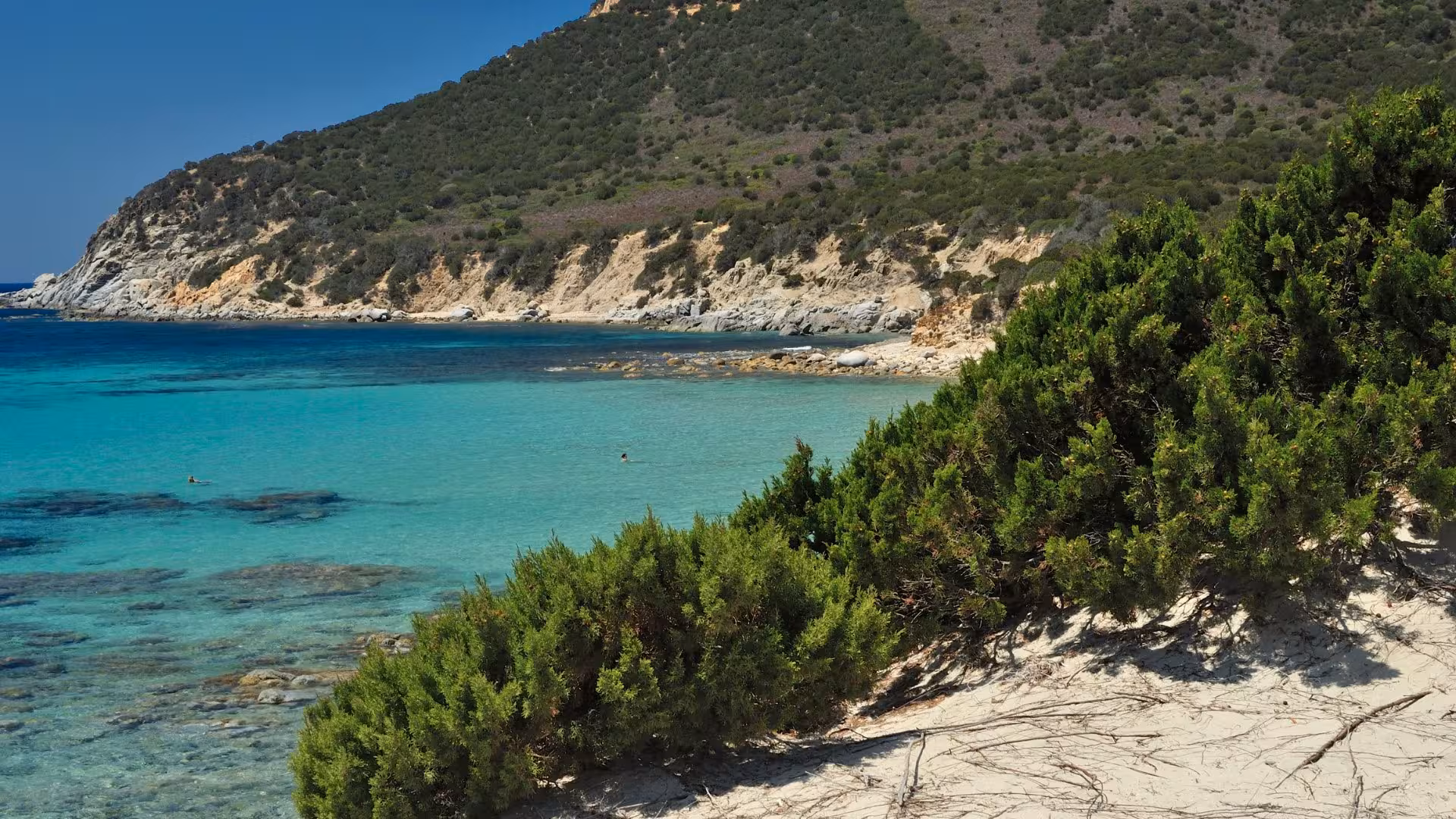 Crystal-clear sea with lush greenery and rocky coastline at Villasimius, an ideal spot for nature lovers in Cagliari tours.