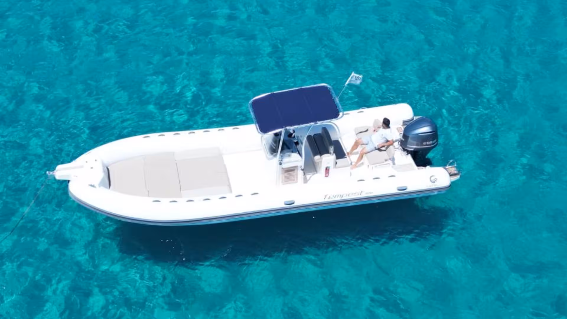 Aerial view of a dinghy cruising over Villasimius' crystal-clear waters, perfect for a scenic Sardinian tour.