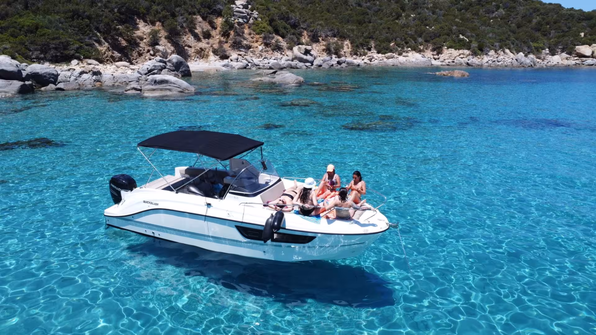 Group enjoying a private boat tour on clear turquoise waters near rocky shores in Villasimius.