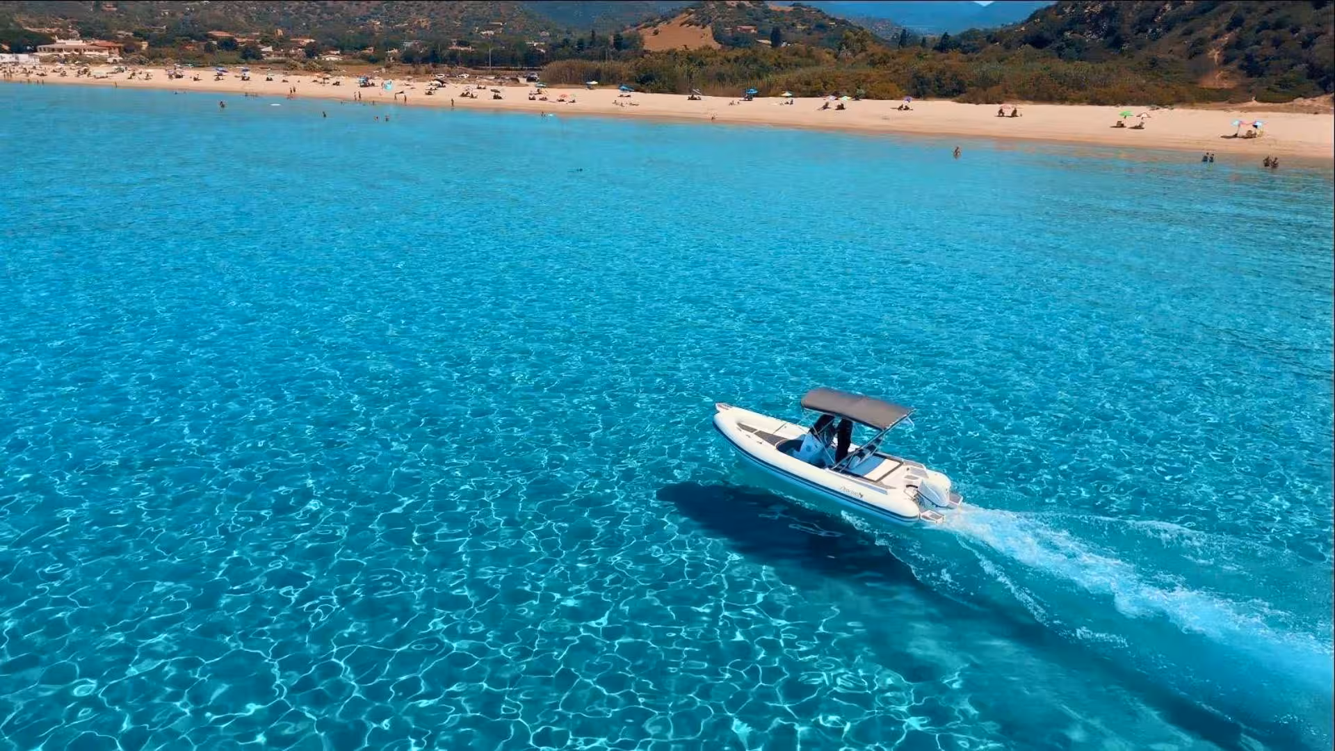 RIB speeding across vibrant blue waters near Villasimius beach, offering an exciting experience for up to 8 people.