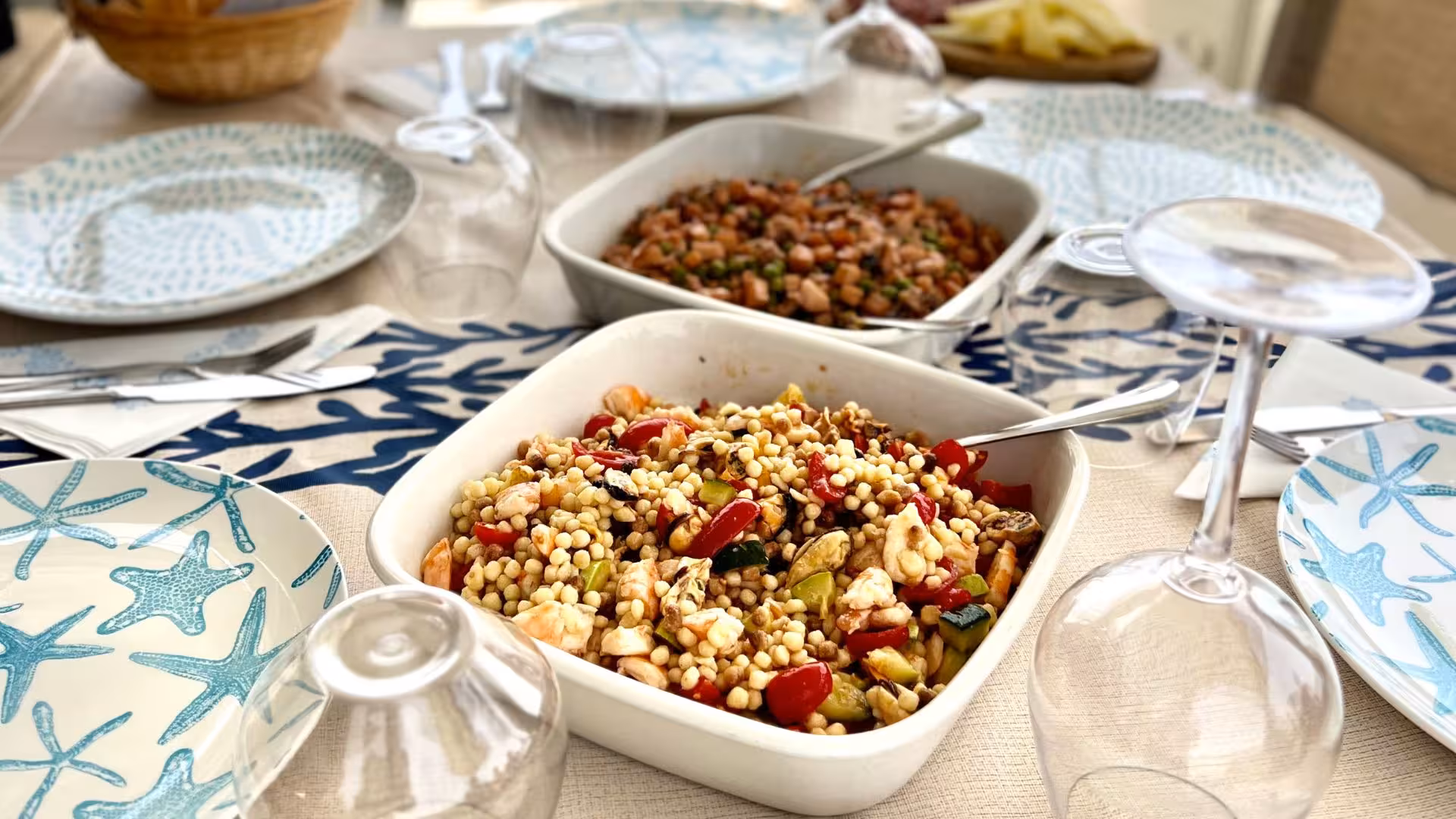 Gourmet seafood and couscous dishes elegantly arranged on a yacht dining table, enhancing Villasimius yacht tours.