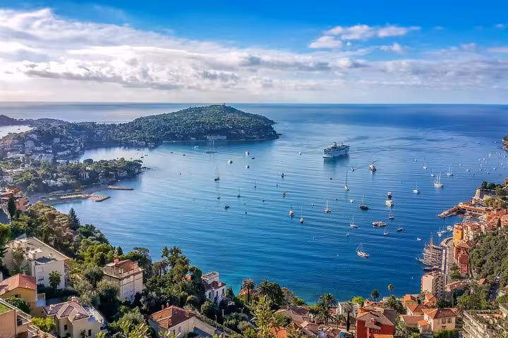Aerial view of Villefranche-sur-Mer bay with turquoise waters, sailboats, and colorful hillside buildings on French Riviera