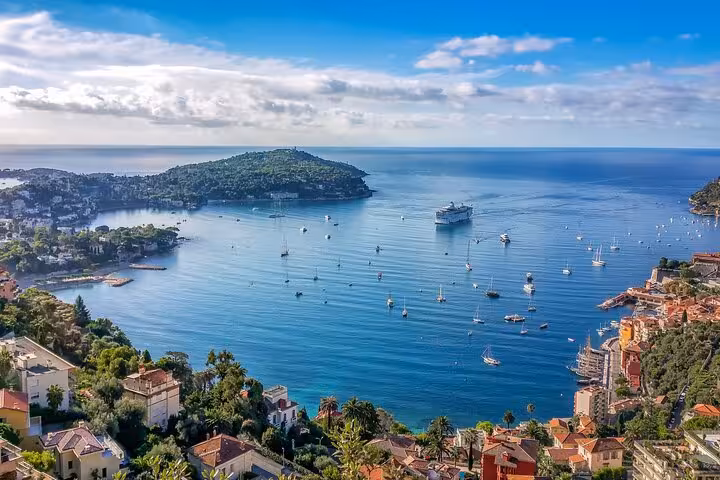 Panoramic view of Villefranche-sur-Mer bay with cruise ship, sailboats, and French Riviera coastline