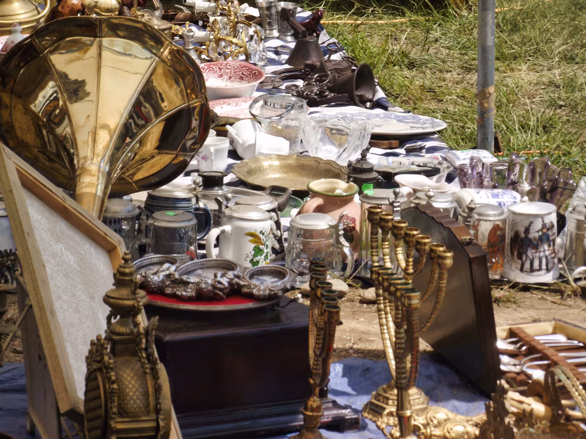 Vintage brass gramophone candlesticks ceramic mugs and antiques at Negreni Flea Market outdoor stall Romania