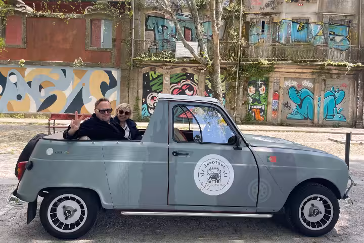 Couple riding a vintage convertible on a Porto city tour, stopping by colorful street art and historic sites