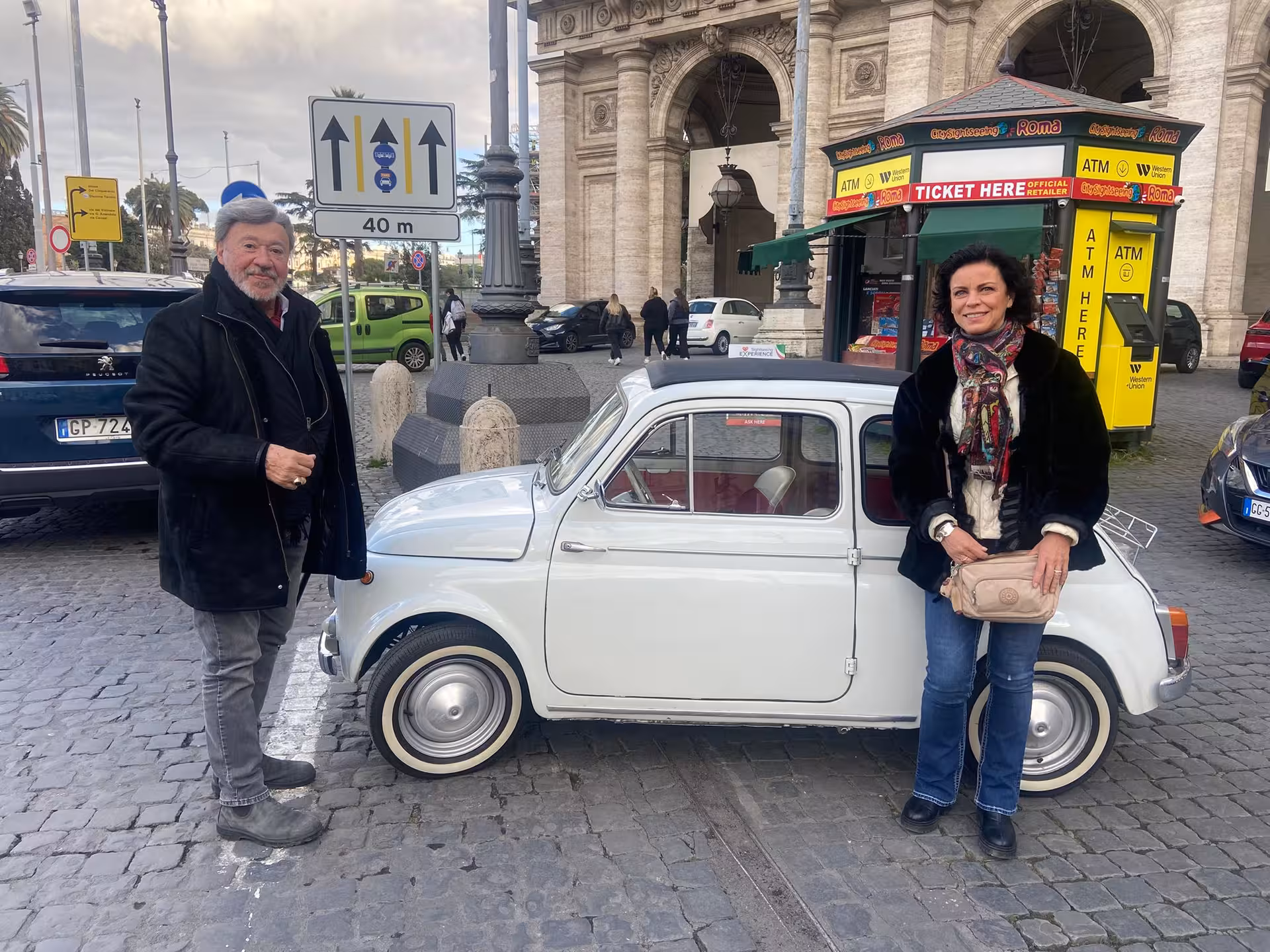 Tourists posing with a vintage white Fiat '500 in Rome, part of The Roman Hills Vintage Tour by Fiat '500.